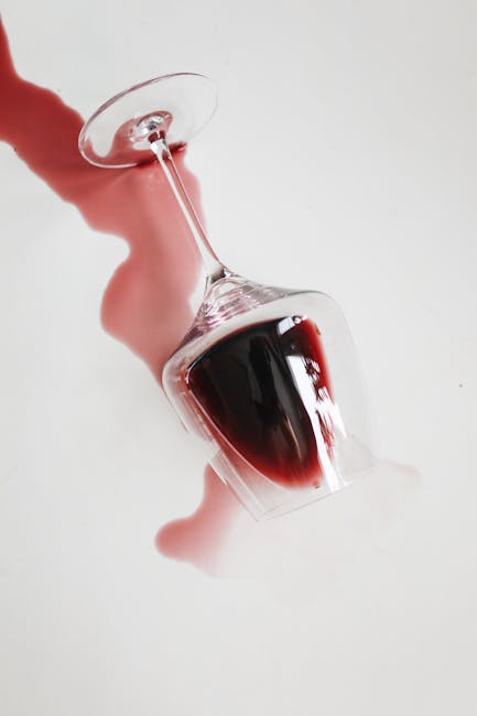 A top-down view of a white surface with visible cracks and black markings, featuring a coffee mug filled with dark coffee and frothy bubbles on top. Surrounding the mug are several large coffee stains with irregular shapes and splatters, indicating recent spills. The surface appears to be a desk or countertop with a matte finish, and the stains contrast strongly against the white background. Visible in the image are parts of the coffee mug, which is situated centrally, and the stains seem fresh, possibly from recent accidental spills. The scene highlights the importance of surface cleaning and stain removal, as offered by Marylebone Carpet Cleaners, known for their deep cleaning and sanitisation services in Marylebone.
